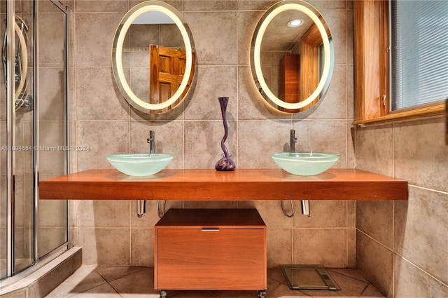 bathroom with an enclosed shower, tile patterned flooring, tile walls, and sink