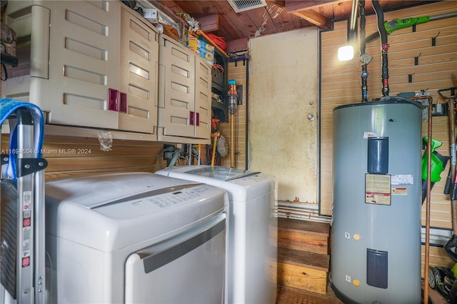 clothes washing area featuring washer and dryer, cabinets, wooden walls, and water heater