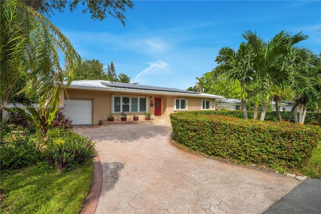 single story home with a garage and solar panels