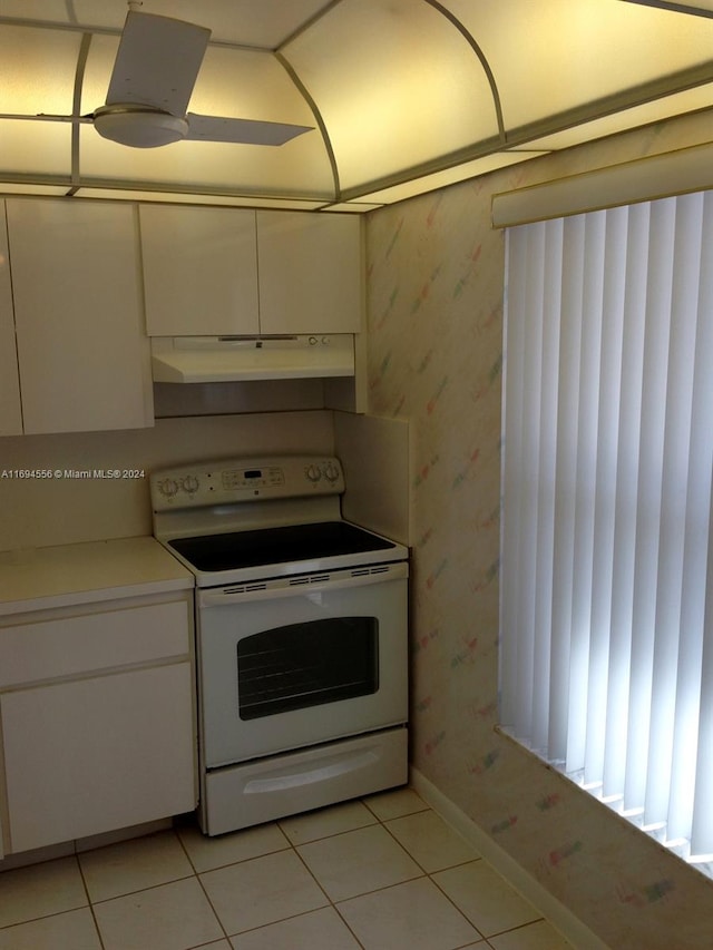 kitchen featuring electric range, white cabinets, and light tile patterned flooring