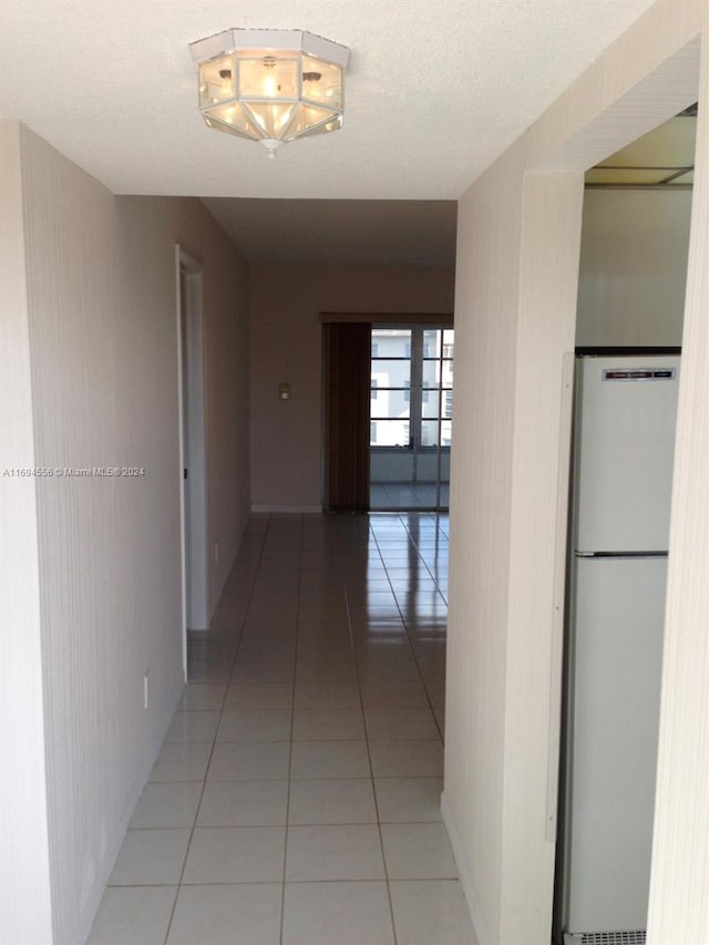 corridor with light tile patterned flooring, a textured ceiling, and french doors