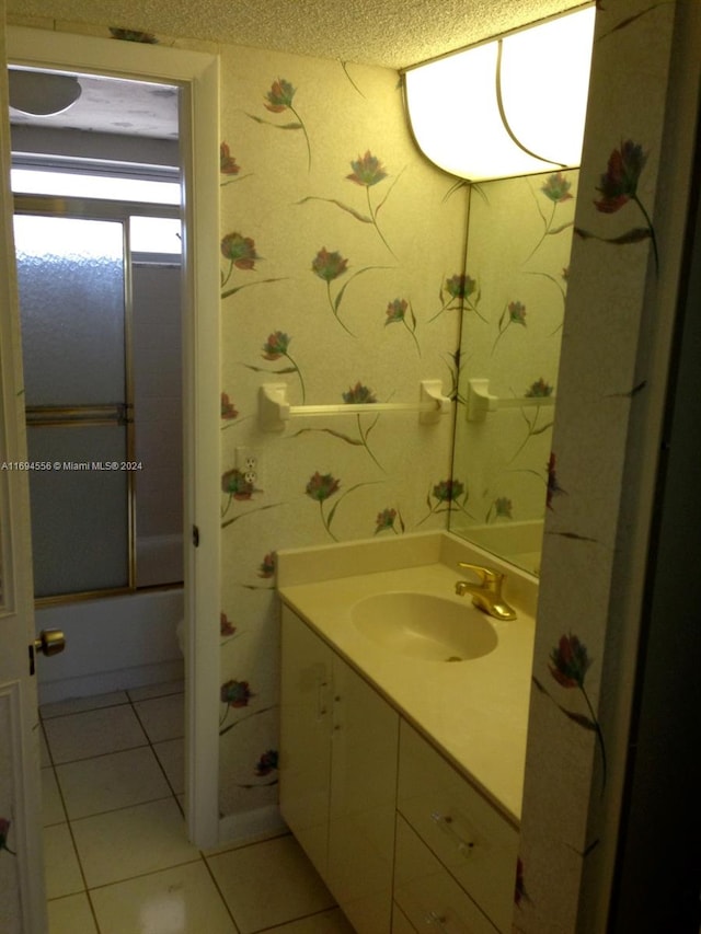 bathroom with tile patterned flooring, vanity, a textured ceiling, and combined bath / shower with glass door