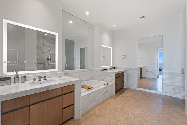 bathroom with vanity and shower with separate bathtub