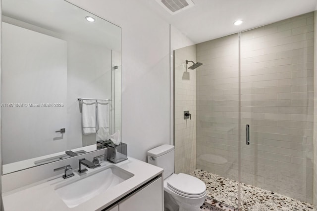 bathroom featuring vanity, a shower with shower door, and toilet