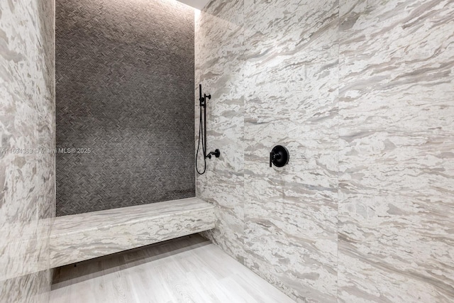 bathroom with tiled shower and wood-type flooring