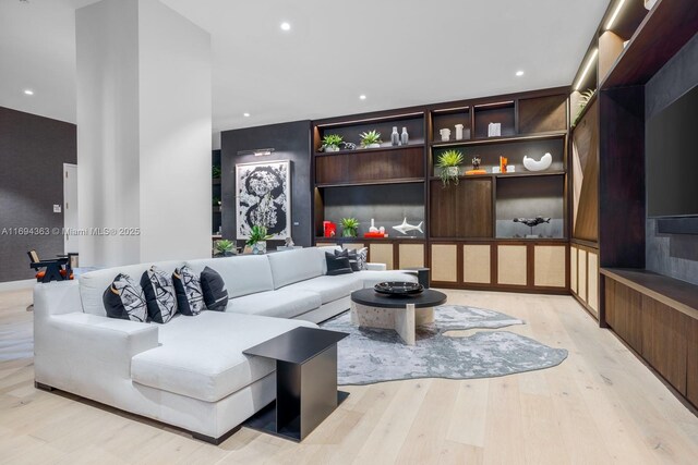 living room with built in shelves and light wood-type flooring