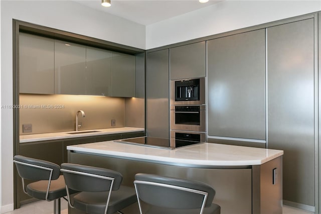 18975 Collins Ave Unit 3402, Sunny Isles Beach, FL 33160 - kitchen featuring stainless steel oven, gray cabinets, black electric stovetop, a breakfast bar area, and a sink