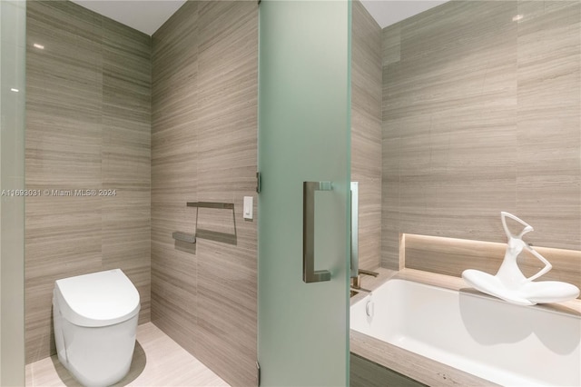 bathroom with a tub to relax in, toilet, and tile walls