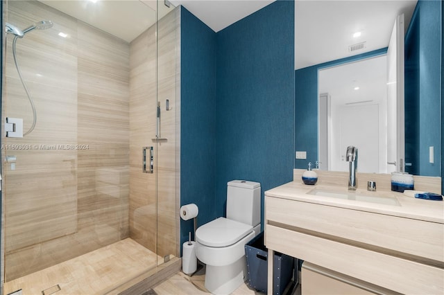 bathroom featuring tile patterned flooring, vanity, toilet, and a shower with door