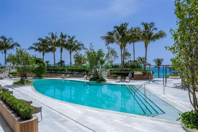 view of swimming pool featuring a water view and a patio