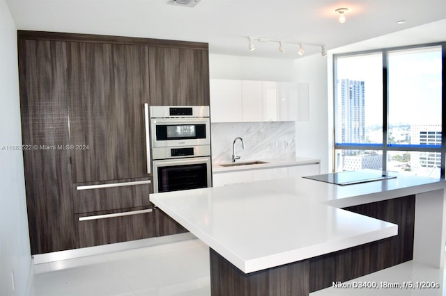 kitchen featuring white cabinetry, sink, stainless steel double oven, decorative backsplash, and black electric stovetop