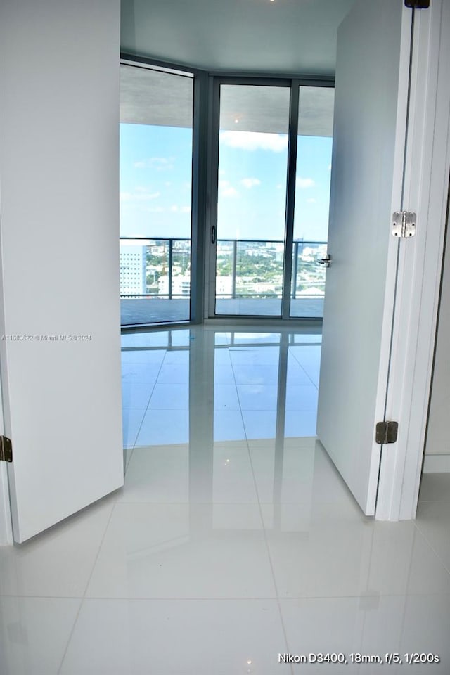 tiled empty room featuring a wall of windows