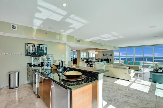 kitchen with a water view, stainless steel refrigerator, expansive windows, and dark stone countertops