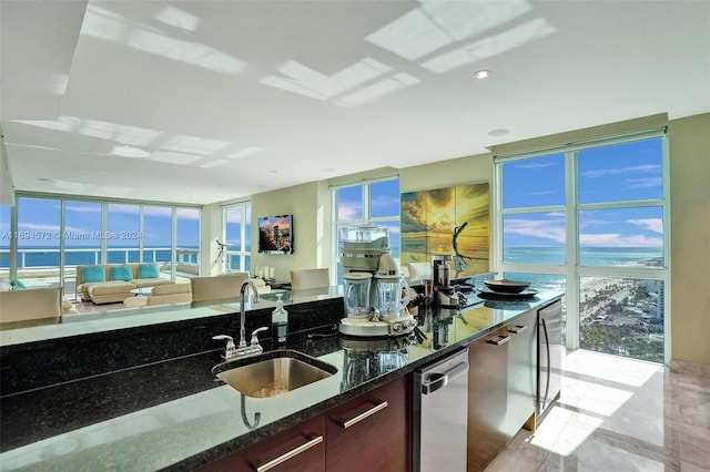 kitchen featuring a water view, expansive windows, dark stone counters, and sink