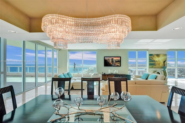 dining room with a wealth of natural light, a water view, and an inviting chandelier