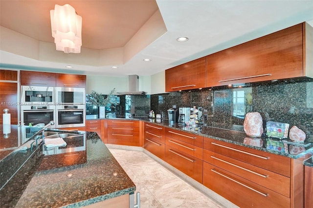 kitchen featuring decorative backsplash, stainless steel double oven, and dark stone counters