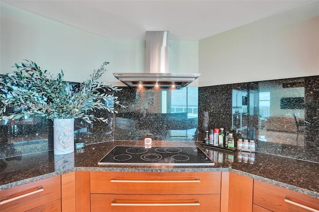 kitchen with tasteful backsplash, black electric stovetop, dark stone counters, and exhaust hood