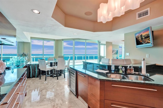 kitchen with wine cooler, dark stone counters, and sink