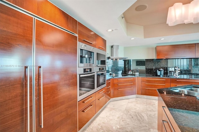 kitchen featuring decorative backsplash, black electric stovetop, dark stone countertops, paneled built in fridge, and range hood