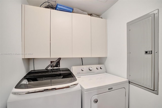 clothes washing area featuring cabinets, electric panel, and washer and dryer