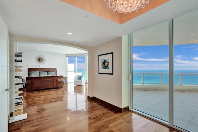 hallway with hardwood / wood-style flooring, a notable chandelier, and a water view