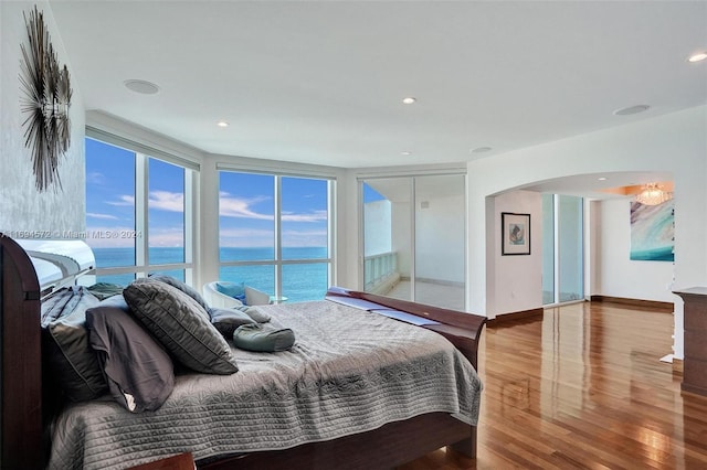 bedroom with wood-type flooring and a water view