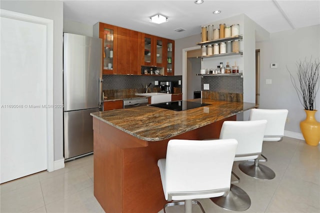 kitchen with kitchen peninsula, decorative backsplash, light tile patterned floors, and stainless steel appliances