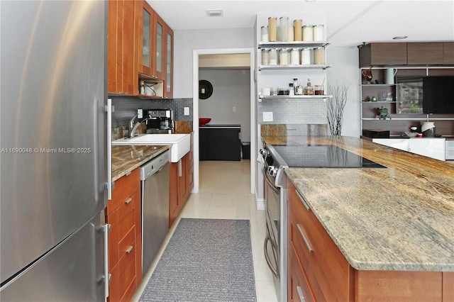 kitchen featuring light stone countertops, sink, tasteful backsplash, light tile patterned flooring, and appliances with stainless steel finishes