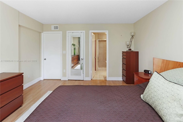 bedroom featuring connected bathroom and light hardwood / wood-style floors