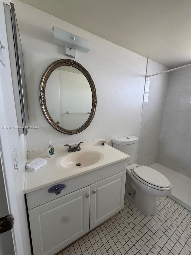 bathroom featuring tile patterned floors, vanity, a tile shower, and toilet