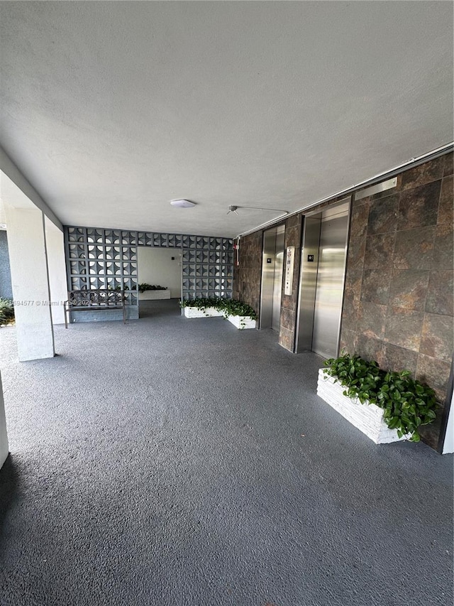 basement with carpet flooring, elevator, and a textured ceiling