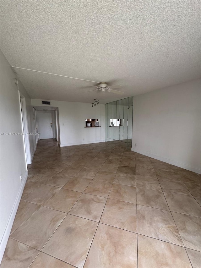 tiled spare room with ceiling fan and a textured ceiling