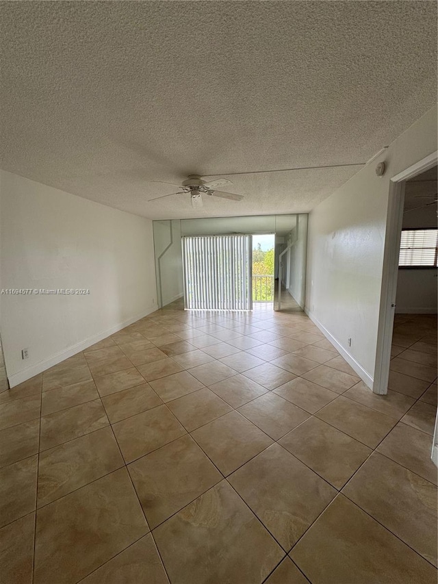 spare room featuring ceiling fan, light tile patterned floors, and a textured ceiling