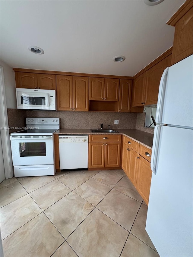 kitchen featuring tasteful backsplash, sink, light tile patterned floors, and white appliances