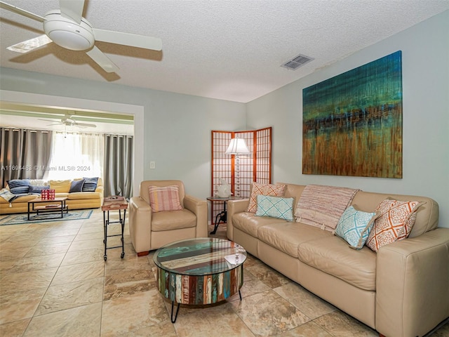 living room featuring a textured ceiling and ceiling fan