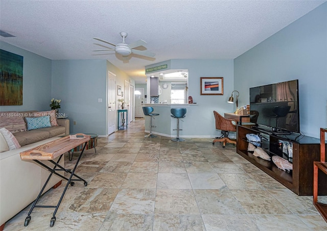 living room featuring ceiling fan and a textured ceiling