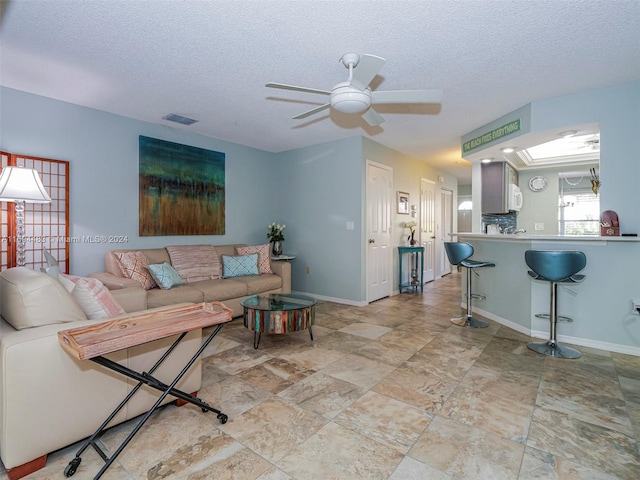 living room with a textured ceiling and ceiling fan