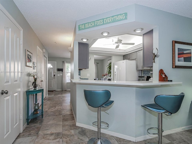 kitchen with a breakfast bar, white fridge, and gray cabinets