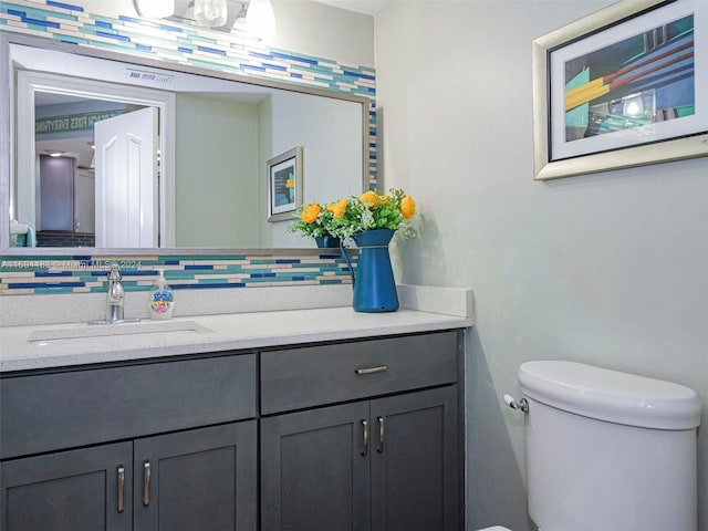 bathroom featuring vanity, toilet, and tasteful backsplash