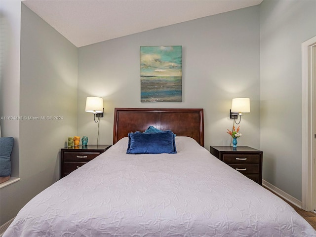 bedroom with hardwood / wood-style floors and lofted ceiling