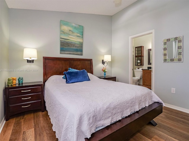 bedroom featuring connected bathroom, dark hardwood / wood-style floors, and vaulted ceiling