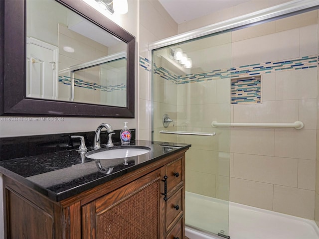 bathroom featuring a shower with door and vanity