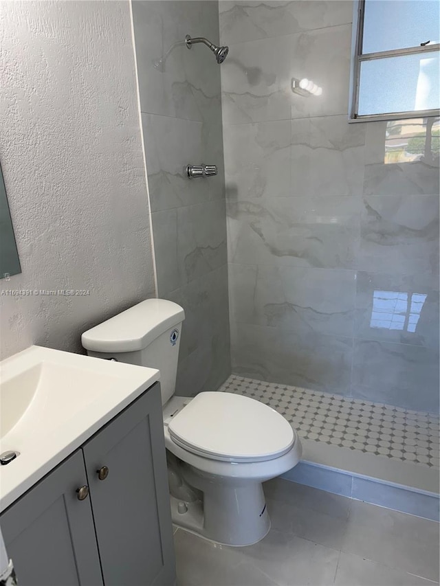 bathroom with a tile shower, vanity, and toilet