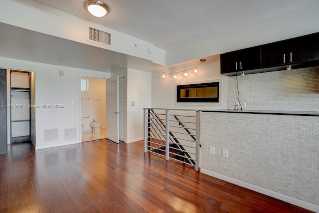 interior space featuring a textured ceiling, dark wood-type flooring, and brick wall