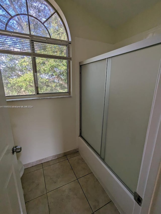 bathroom featuring tile patterned flooring and shower / bath combination with glass door