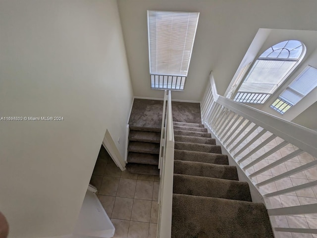 staircase with tile patterned flooring and a high ceiling