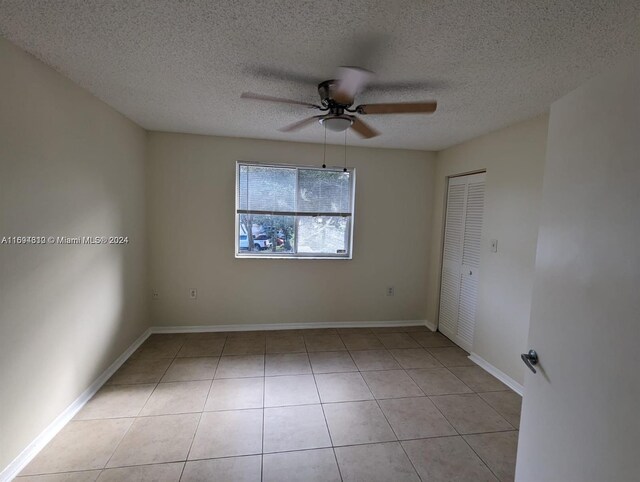 spare room featuring a textured ceiling, ceiling fan, and light tile patterned flooring