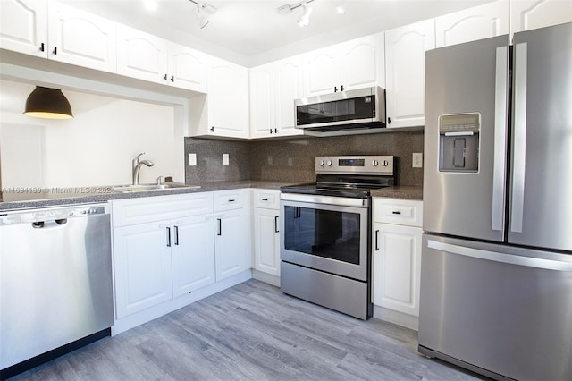 kitchen featuring white cabinetry, backsplash, appliances with stainless steel finishes, and light hardwood / wood-style flooring