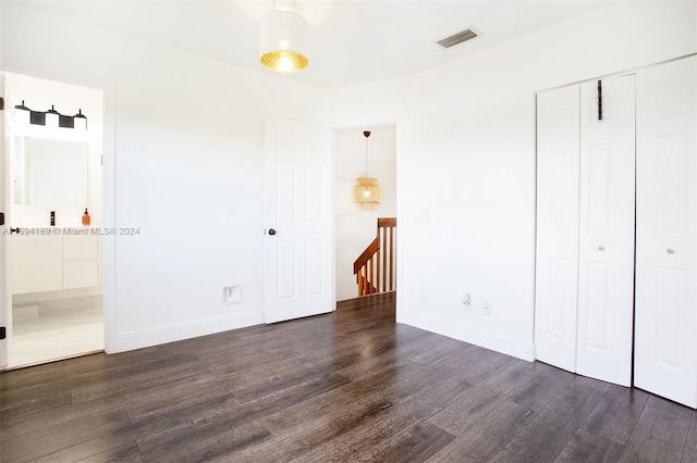 unfurnished bedroom featuring a closet and dark wood-type flooring