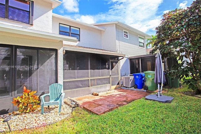 rear view of house with a sunroom, a yard, and central air condition unit